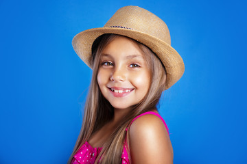 Portrait of young cute girl in pink dress and hat on blue background .Summer vacation and travel concept