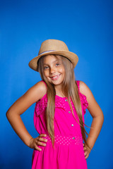 Naklejka premium Portrait of young cute girl in pink dress and hat on blue background .Summer vacation and travel concept