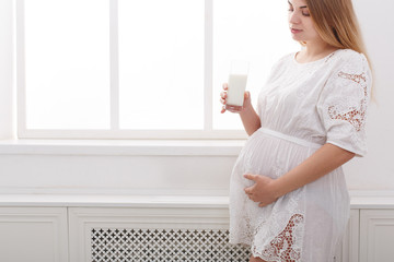 Pregnant woman drinking glass of milk copy space
