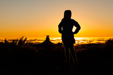 Silhouette girl in backlight on mountain summit at sunset