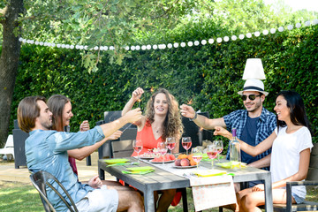 group of friends having fun picnic lunch party outdoor in backyard during summer holiday vacation