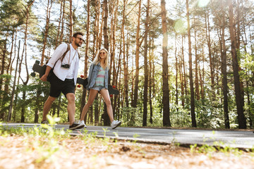 Obraz premium Loving couple walking with skateboards outdoors.