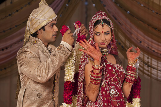 Indian groom trying to put a garland on his bride 