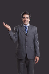 Portrait of confident businessman showing invisible product over black background