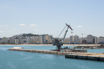 Marocco: una gru nel porto e lo skyline di Tangeri, città marocchina sulla costa del Maghreb all'entrata occidentale dello stretto di Gibilterra, dove il Mar Mediterraneo incontra l'Oceano Atlantico