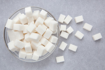 White sugar cubes on gray background from top view