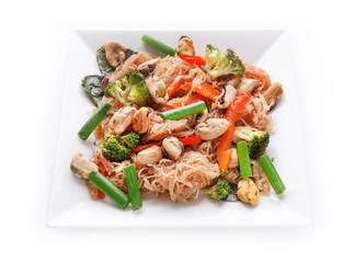 Funchoza salad with rice noodles, mussels and vegetables on white dish isolated on a white background