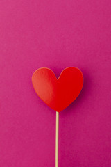 Paper heart on a stick over a bright pink background
