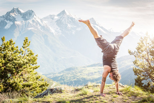 Ragazzo in verticale con panorama di montagna, a testa in giu