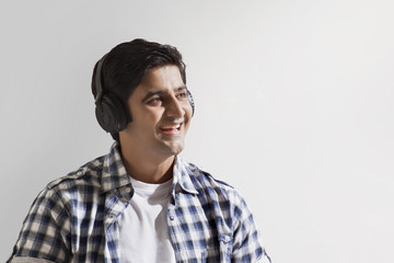 Close-up of smiling young man enjoying music 
