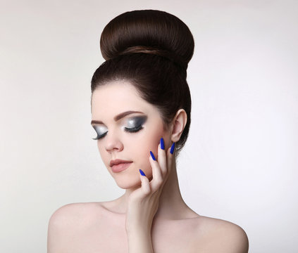 Beauty makeup girl. Fashion bun hairstyle. Manicure nail. Young fresh brunette with natural matte lipstick and glitter eyeshadow isolated on studio background.