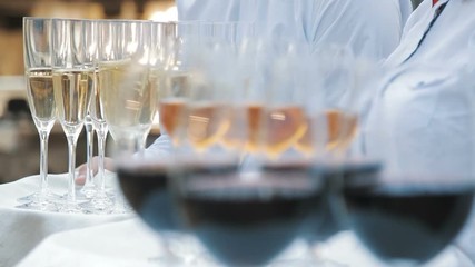 Waiters greet guests with alcoholic drinks. Champagne, red, white wine on trays - Powered by Adobe