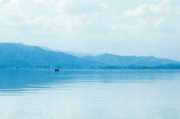 A boat in dam with blue sky and water.