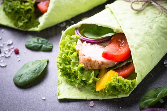 Green spinach tortilla with chicken and vegetables. Fast food healthy snack.