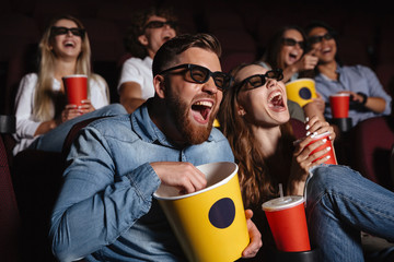 Laughing friends sitting in cinema watch film - obrazy, fototapety, plakaty