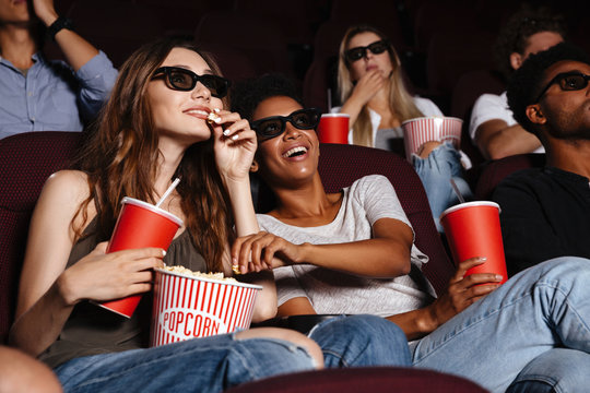 Cheerful friends sitting in cinema watch film