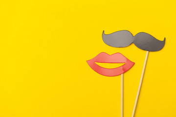 Moustache and lips on a stick on a bright yellow background
