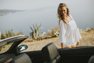 Pretty young woman by the white cabriolet car