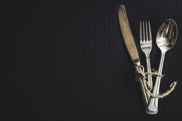 A set of cutlery: a fork, a spoon, a knife - a top view. Black background