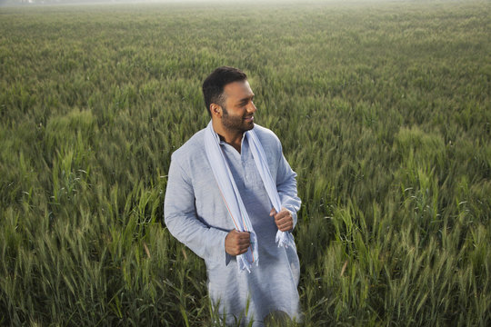 Indian man looking away while standing in a field 