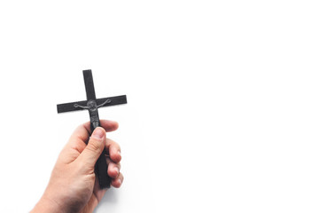 Closeup of wooden christian cross in the hand on the white isolated background. Church utensils. Man holding a crucifix.