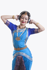 Bharatanatyam dancer listening music on headphones over white background