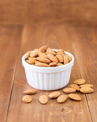 Almonds nuts in white bowl on wooden background