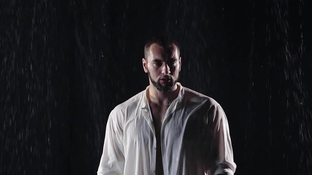 sad big man with big shoulders and a beard the night in the cold rain in wet clothes white. he bowed his head down