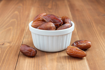 Date fruit in white bowl on wooden background