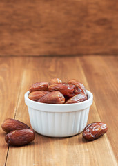 Date fruit in white bowl on wooden background
