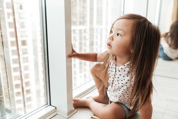 Pretty little cute asian girl at home standing near window