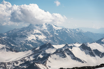 Naklejka premium Dark blue sky with clouds on the rocky peaks of the mountains covered with glaciers and snow