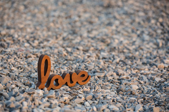 Wooden sign Love on the rocks, in the sunset