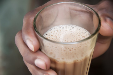 Close-up shot of man's hand holding glass of chai 