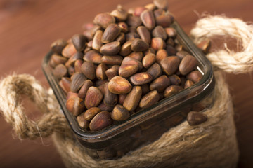 Whole pine nuts in a glass bowl. Wooden background