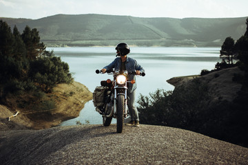 Man pushing motorcycle on rock
