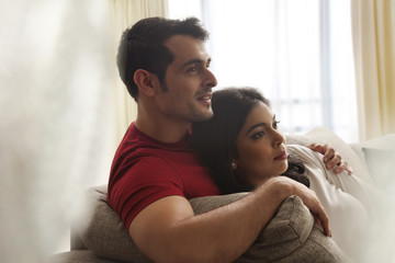 Close-up of young couple sitting on sofa watching television