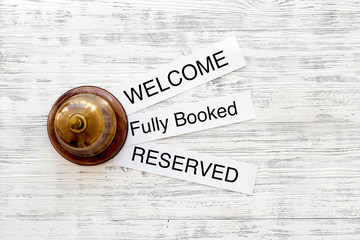 At the hotel. Words welcome, fully booked, reserved on light wooden table top view copyspace
