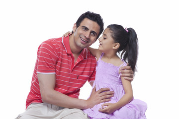 Daughter whispering in father's ear against white background