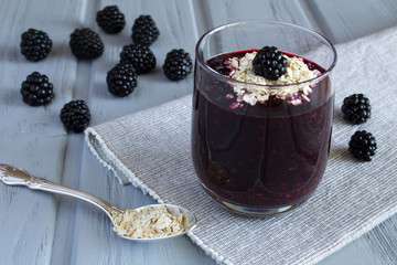 Healthy breakfast. Smoothies with blackberry and oat flakes on the grey background 
