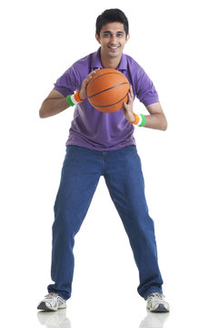 Full length portrait of young man holding basketball over white background 