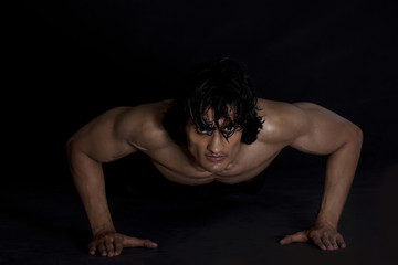 Fototapeta na wymiar Portrait of young man exercising against black background 