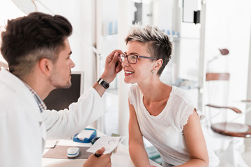 Obraz na płótnie Canvas Male optometrist checking patient's vision at eye clinic. 
