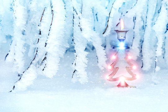 Beautiful christmas tree in a snowy park. A metal candlestick in the form of a New Year's spruce. New Year's art image in blue tones. In the woods the snow falls.