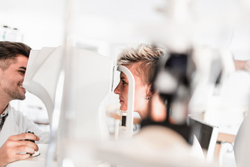Male optometrist checking patient's vision at eye clinic. 