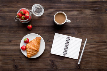 Light summer lunch. Coffee, strawberry, croissant on wooden background top view
