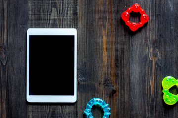 Mockup for adoption concept. Tablet PC near toys on dark wooden background top view copyspace