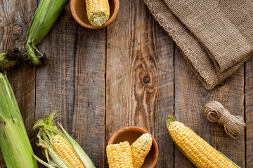Fototapeta na wymiar Organic farm food. Cutted corn cobs on rustic wooden background top view copyspace