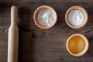 Put the dough. Flour, salt, oil and rolling pin on dark wooden table background top view copyspace