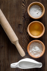 Put the dough. Flour, salt, oil, milk and rolling pin on dark wooden table background top view copyspace
